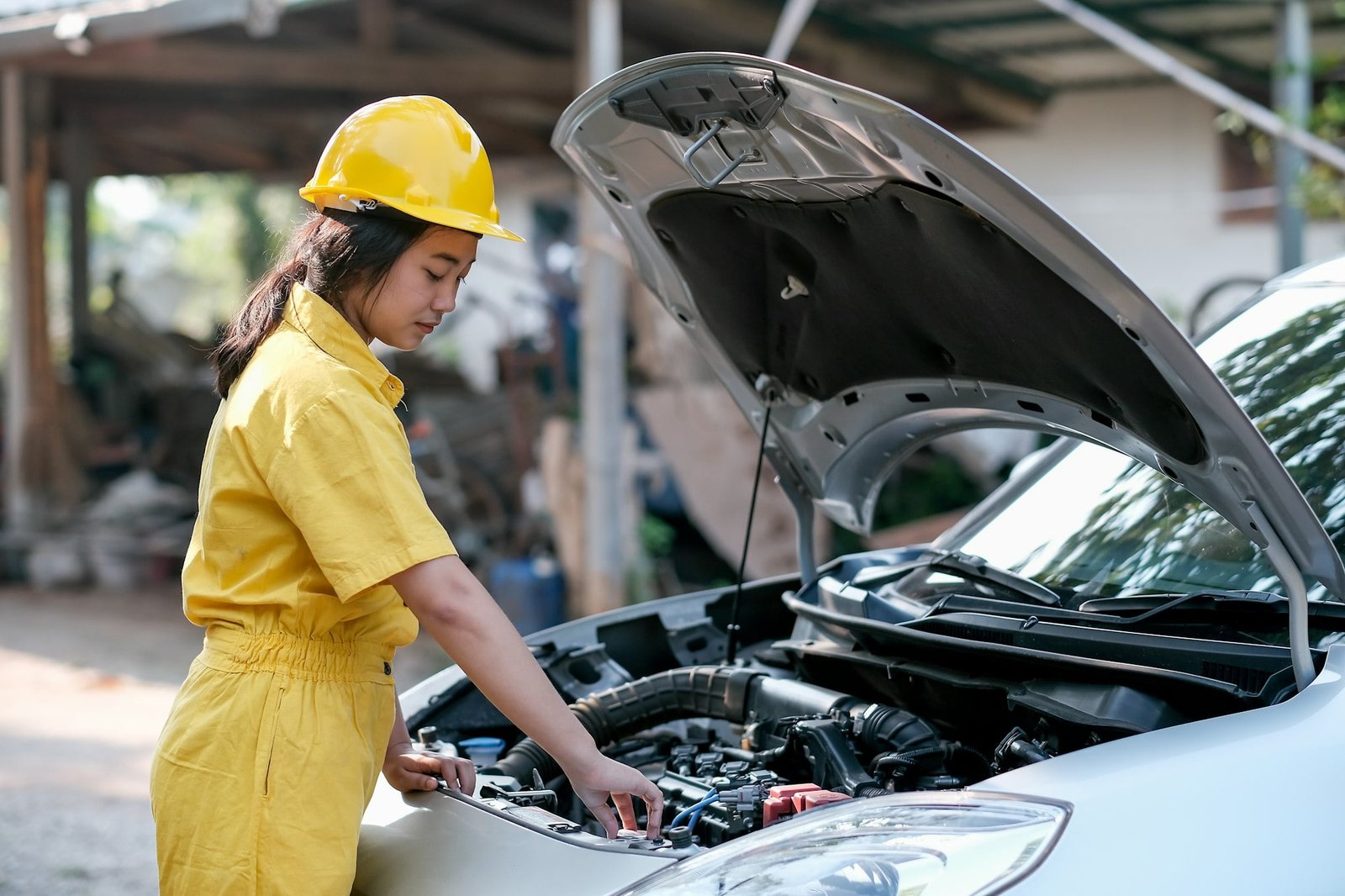 Asian automotive mechanic girl with yellow suit and helmet check the engine and system