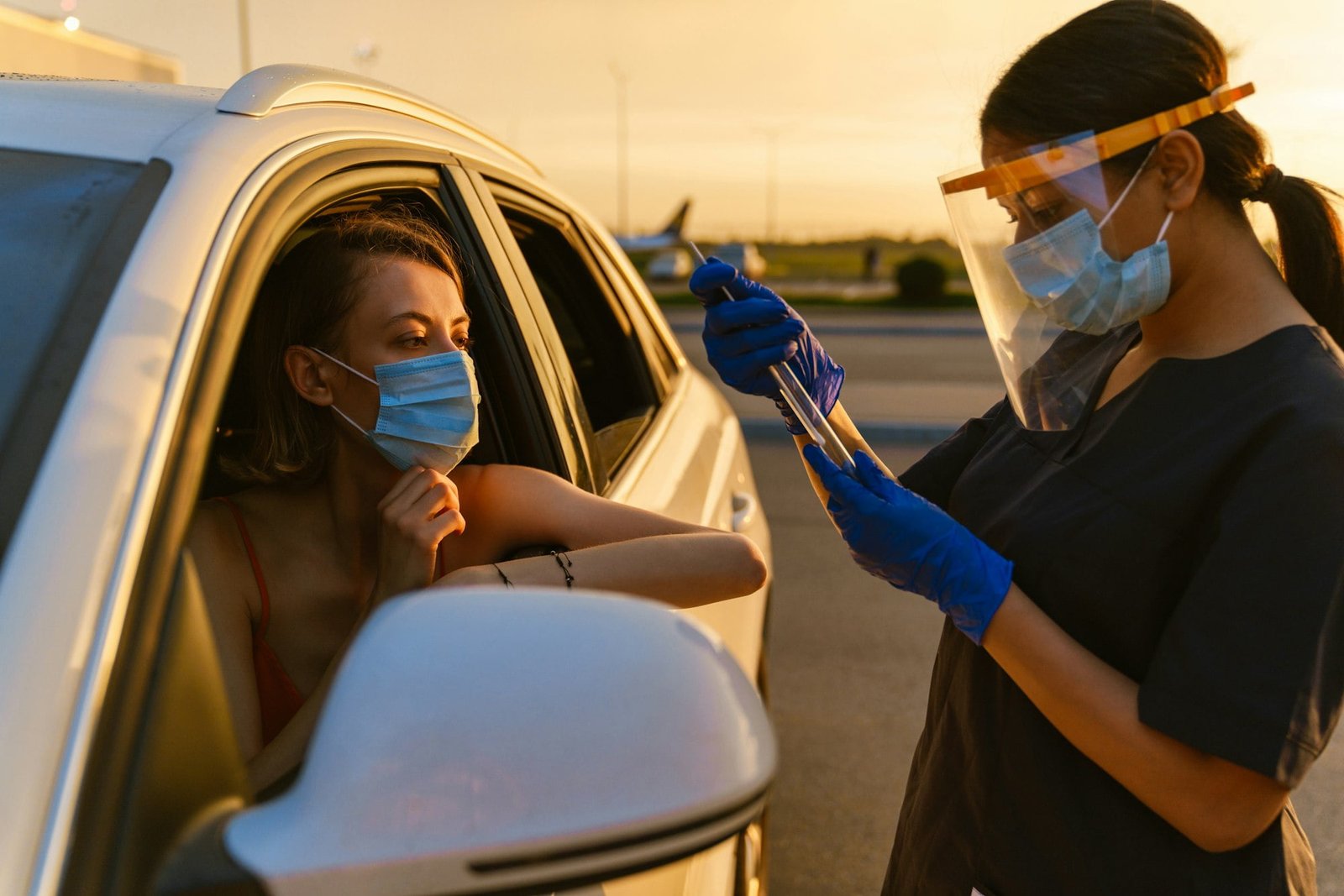 Black health worker making covid test to white woman at car