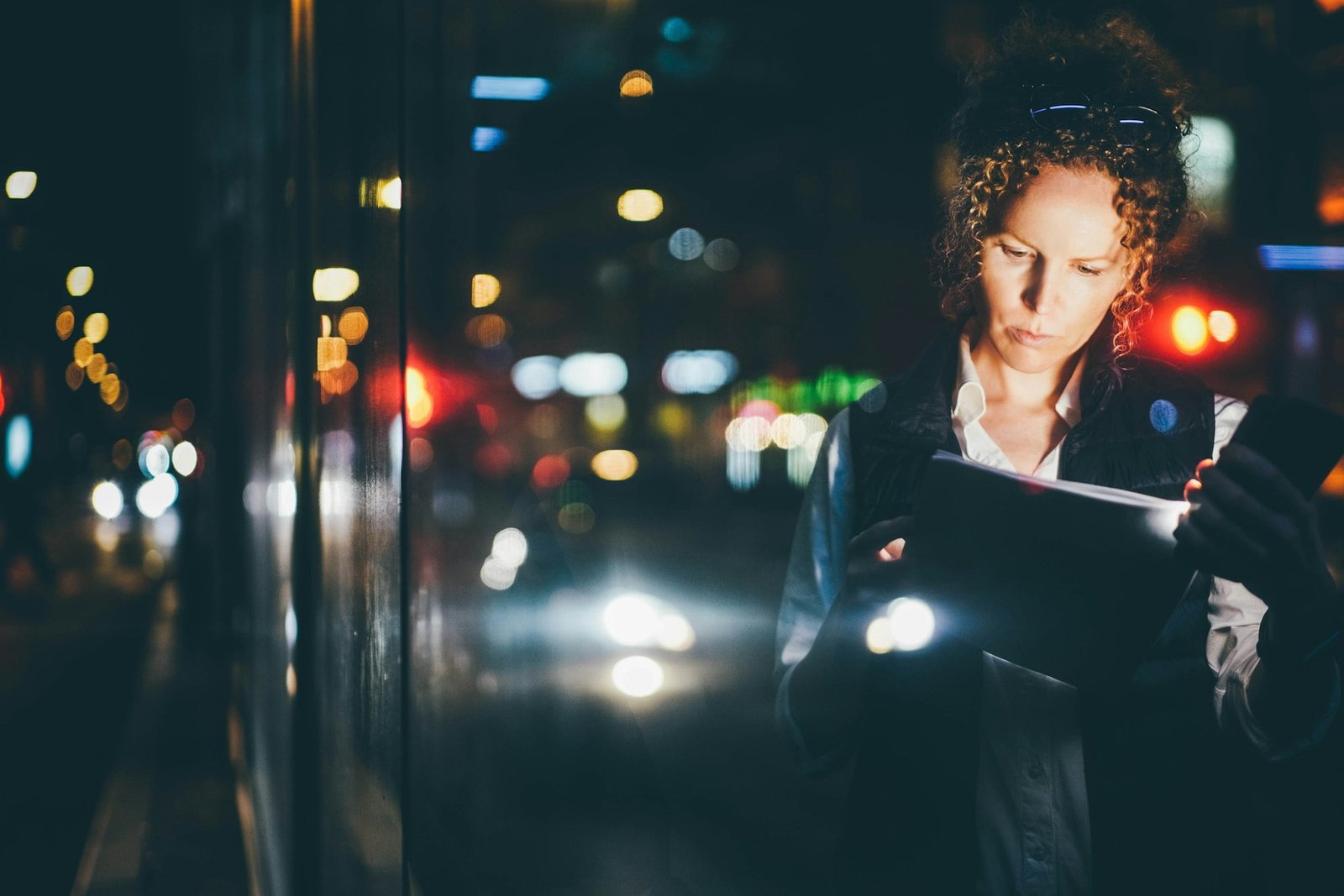 Businesswoman looking to the document while waiting for public transport