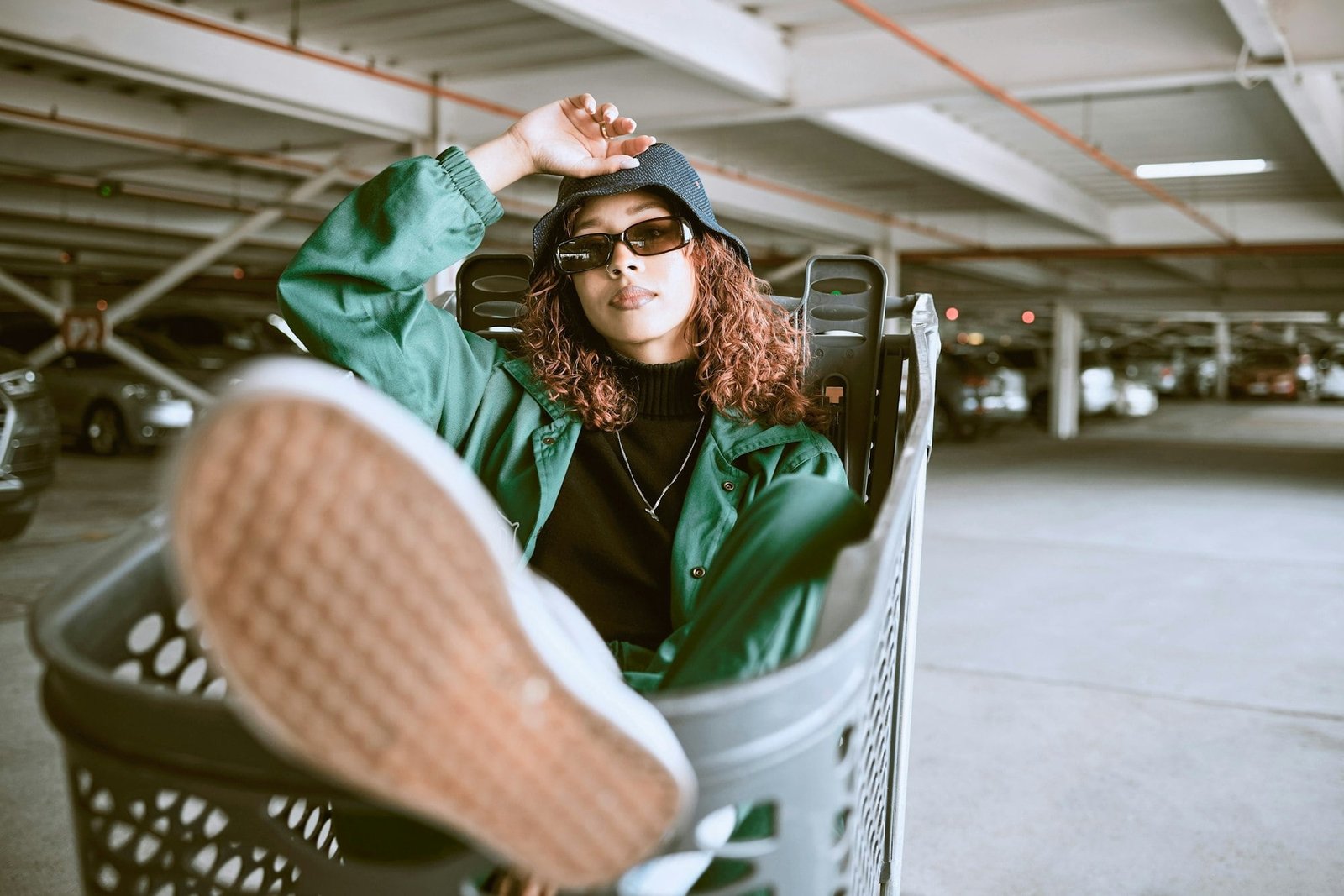 City, parking lot and woman sitting in shopping cart with urban fashion and cars parking in backgro