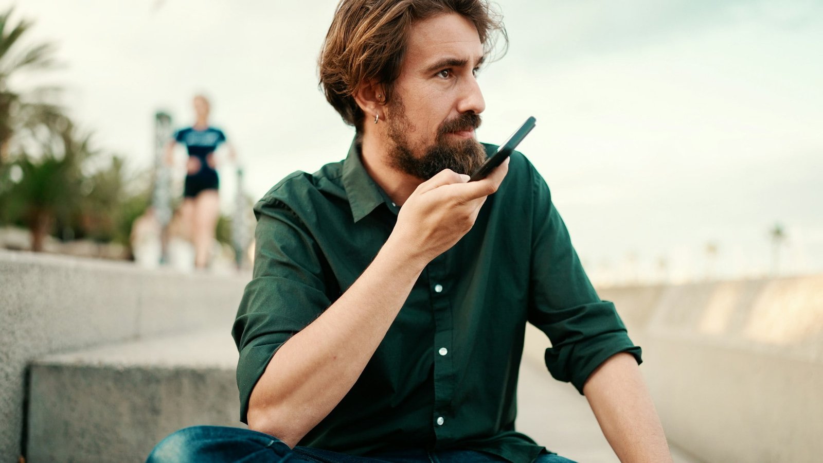 Close-up portrait of a man with a beard recording a voice message on the embankment background