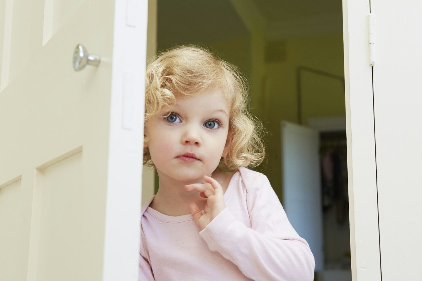 Female toddler peering from door