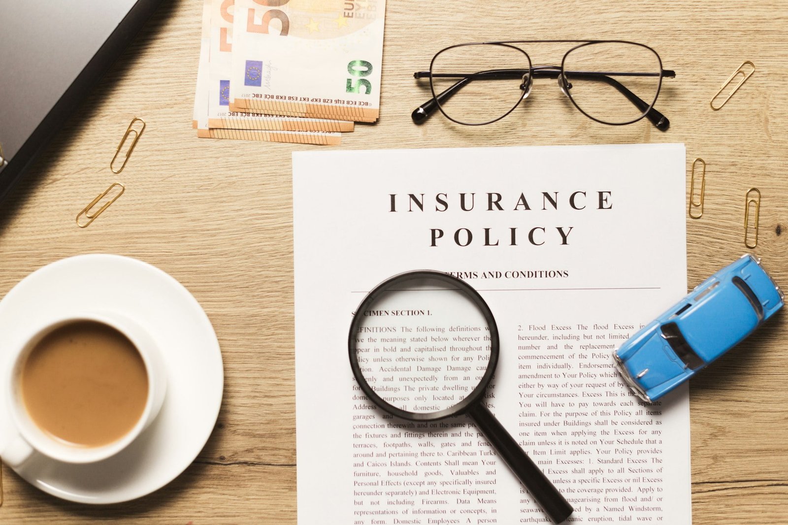 Flat lay of vehicle insurance policy. Magnifier, retro car toy and cash