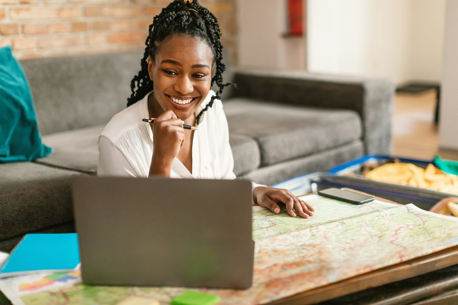 Happy black woman planning vacation with map and laptop, choosing best travel routes for future