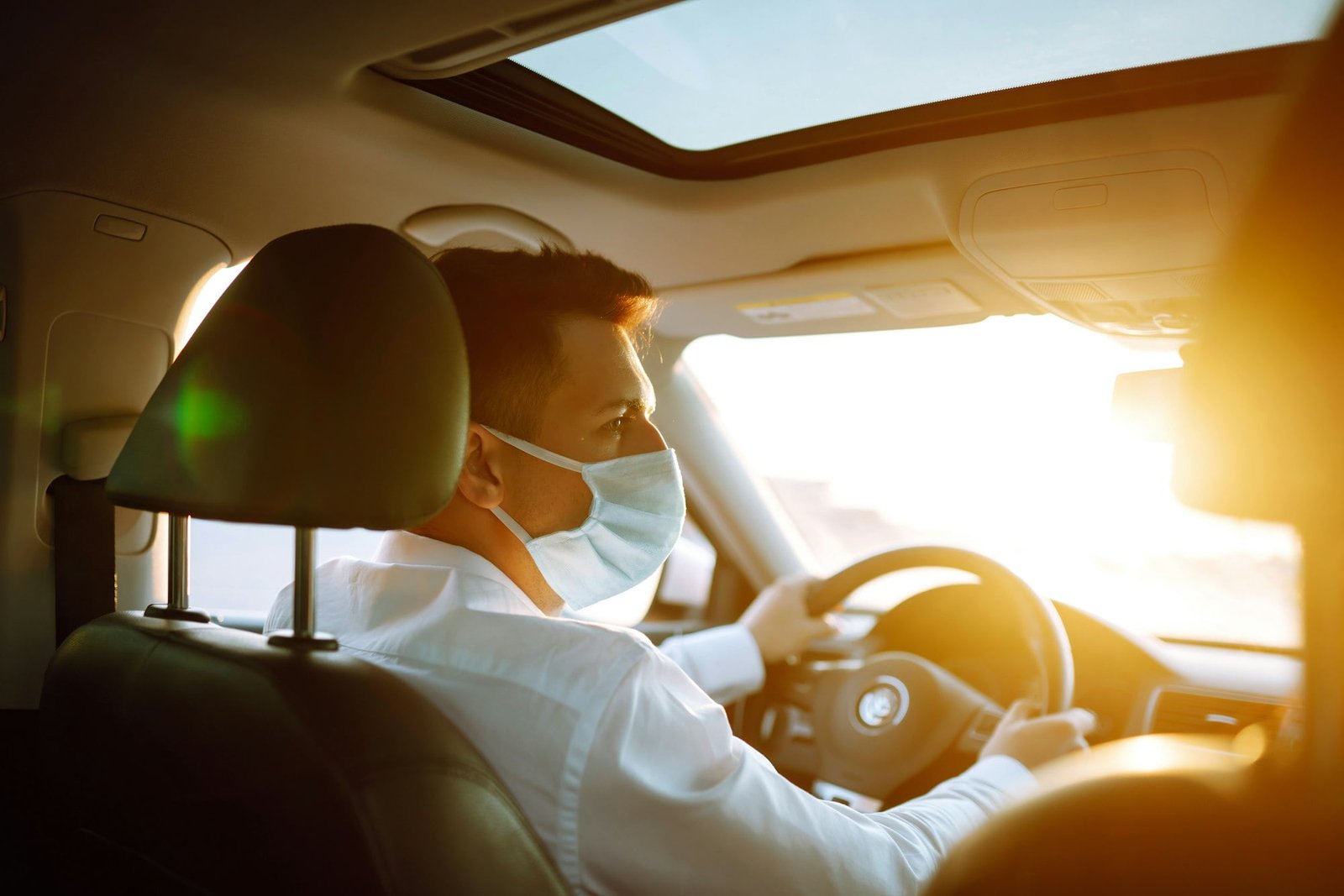 Man driving a car wearing on a medical mask during an epidemic, a driver- taxi in a mask. Covid-2019