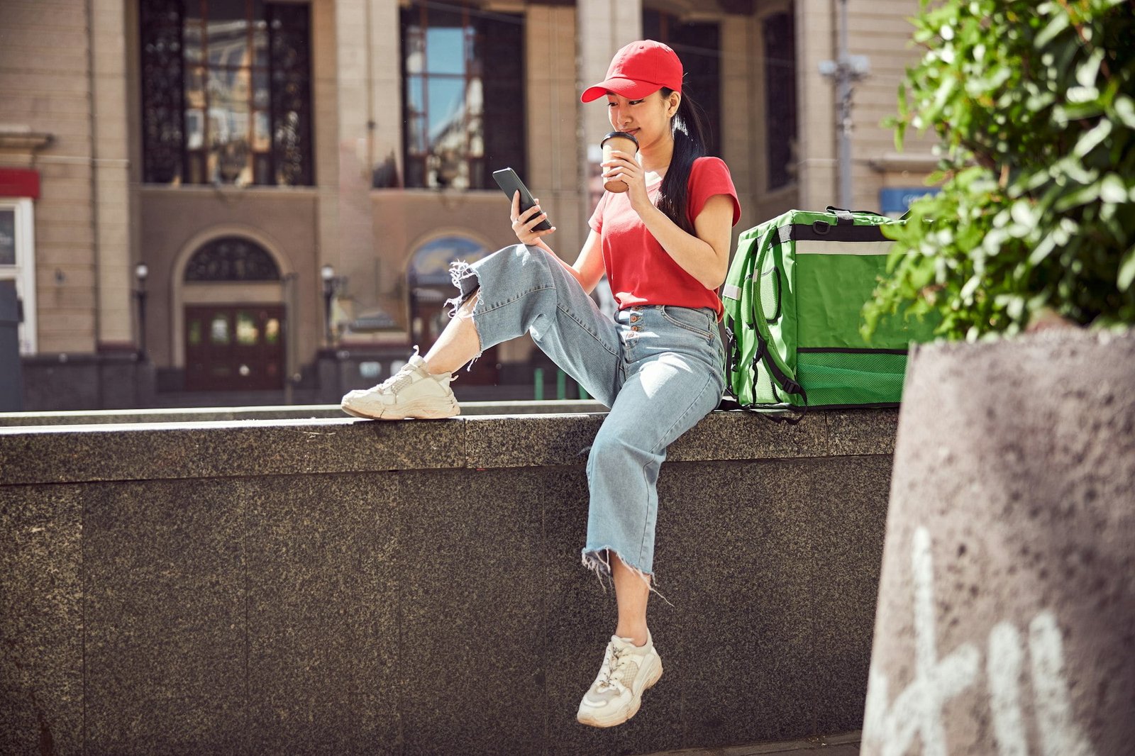 Photo of woman courier resting in urban environment