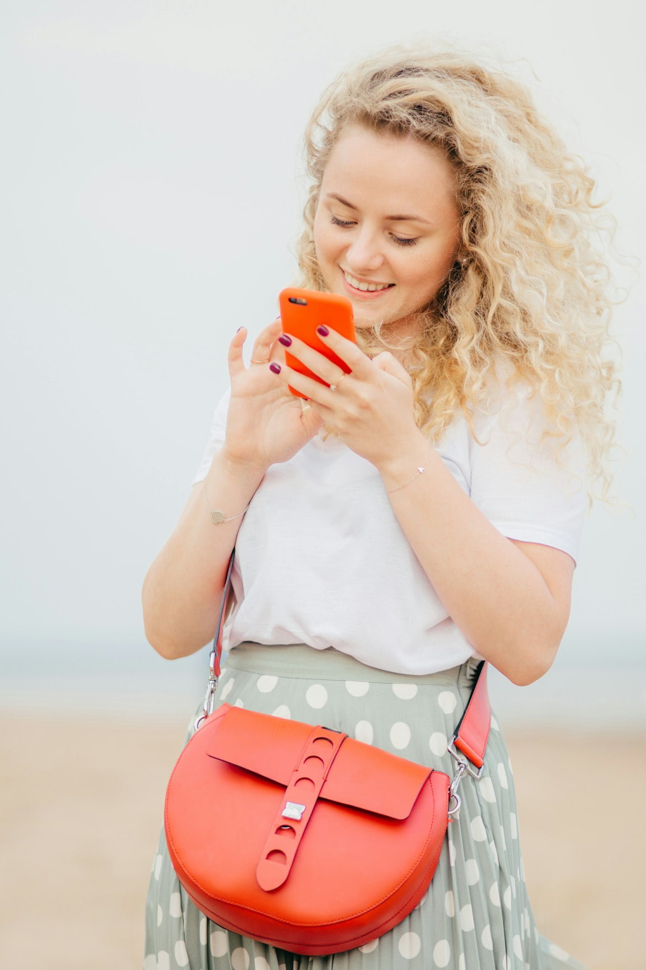 Woman has light curly hair, holds modern cellular, happy to see photo of lover in social networks