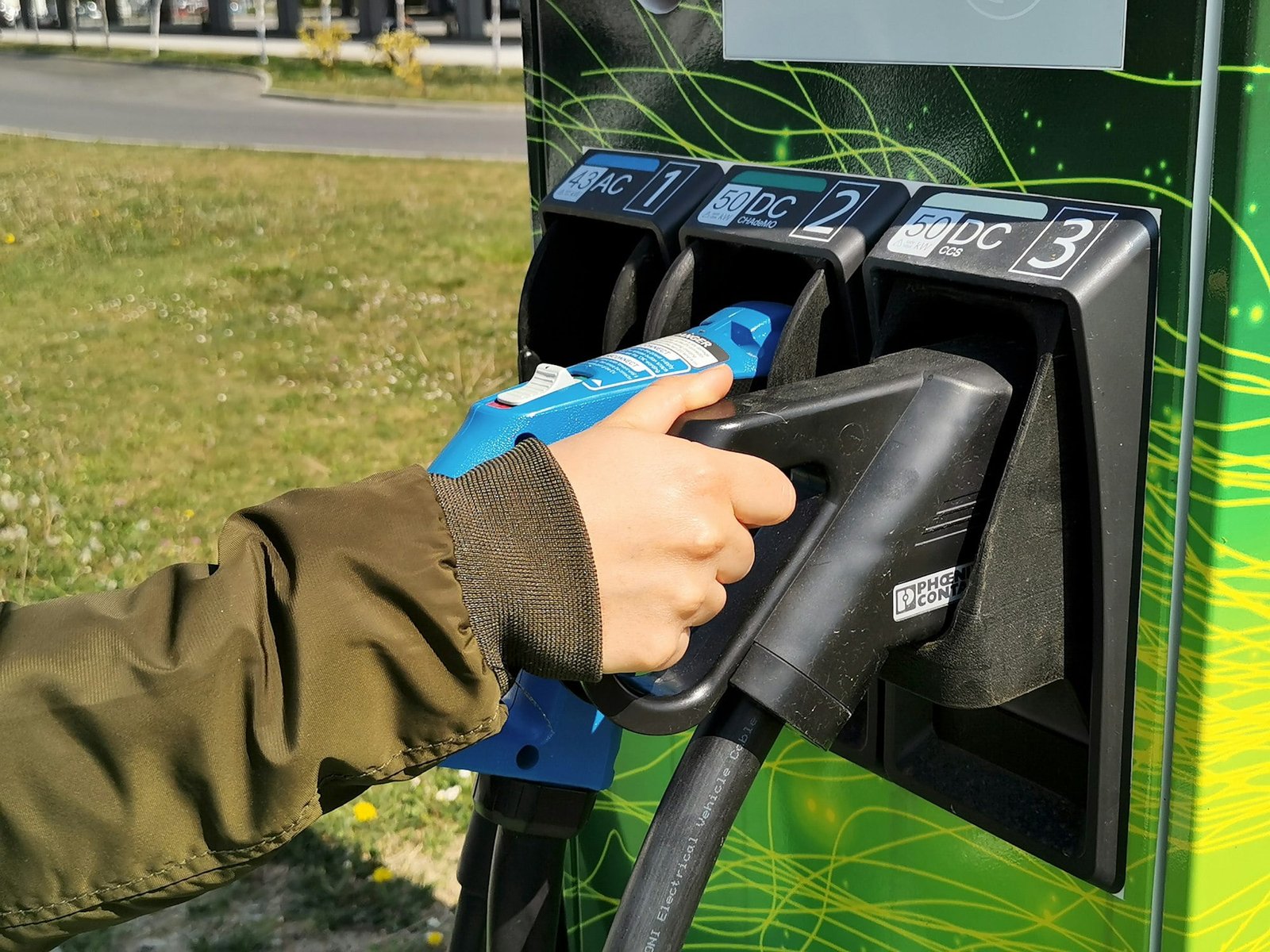 Woman's hand holding electric charging station handle to charge her ev