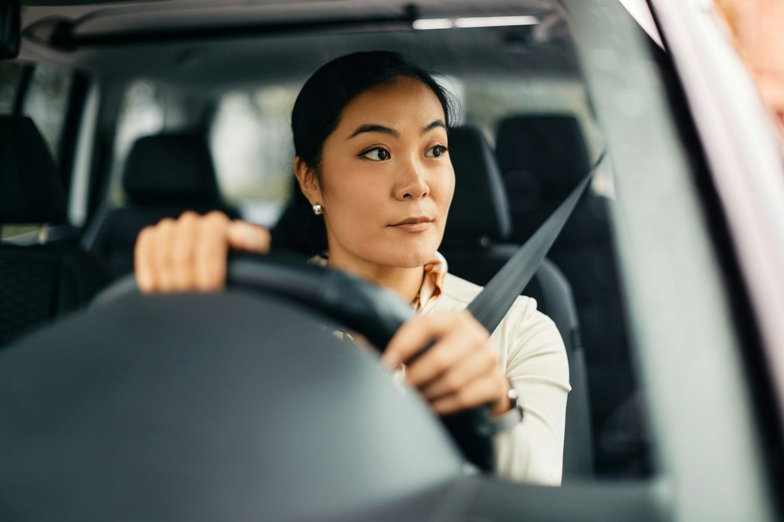 Young Asian woman driving her car in the city.