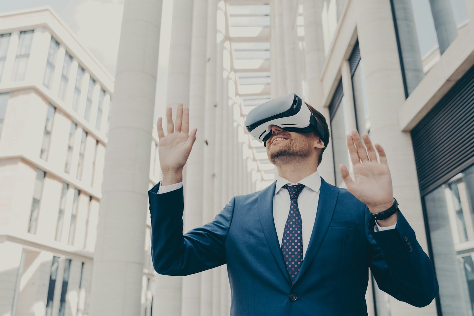 Young modern businessman in VR goggles on head working in augmented reality world and smiling