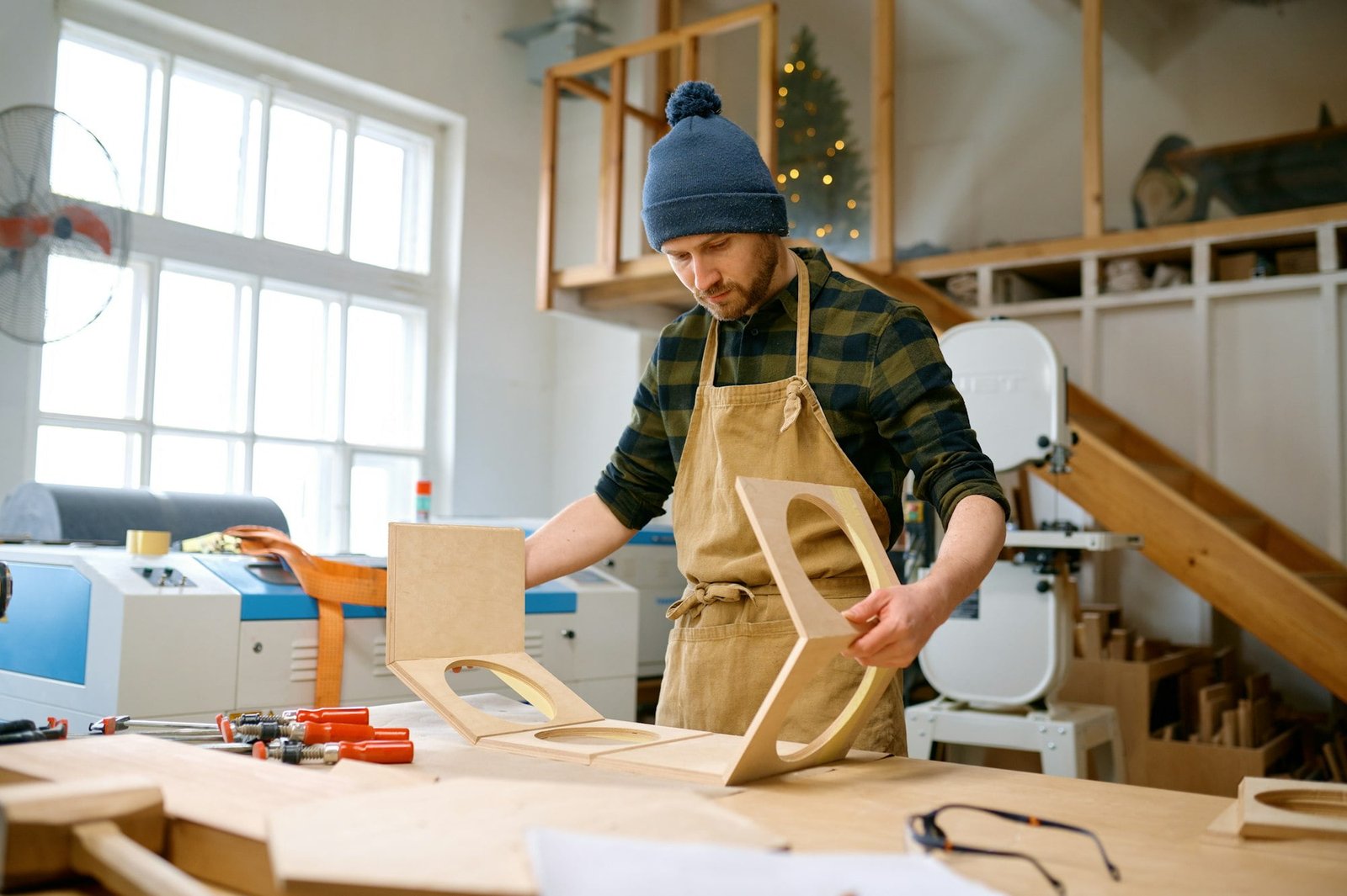 Young pensive man working with wooden material at carpentry studio