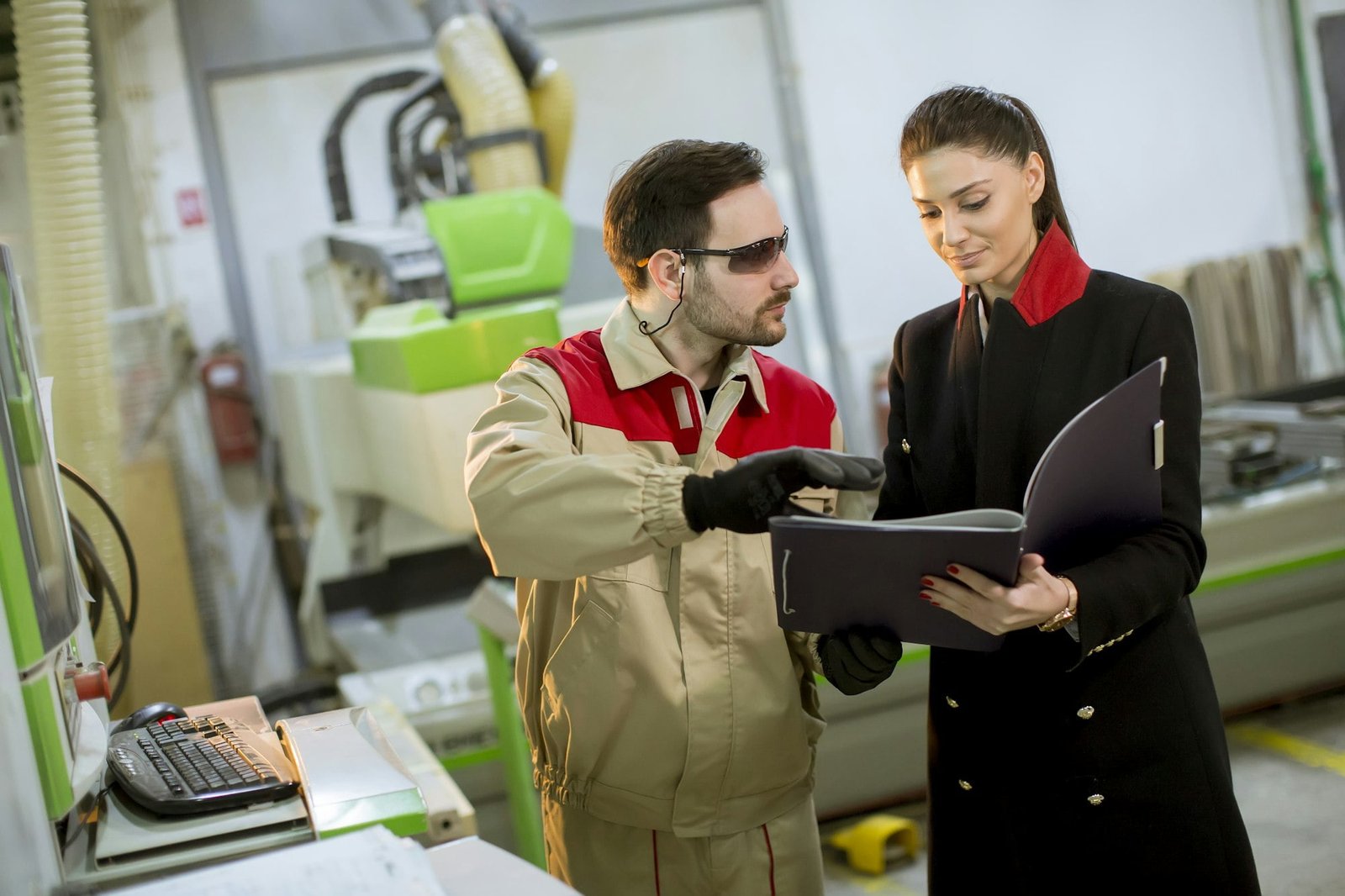 Young woman controlling process in the factory with male worker